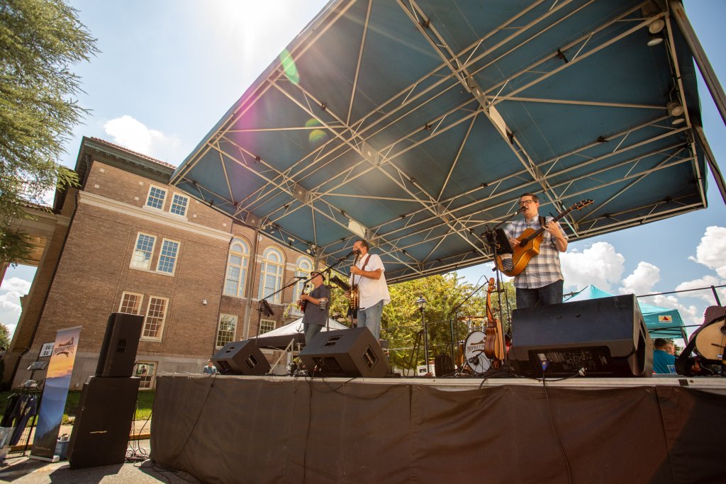 Summerfest in York, South Carolina: Music, Food, and Family Fun A band performs on an outdoor stage at York Summerfest, with sunlight shining over the crowd and historic buildings in the background.