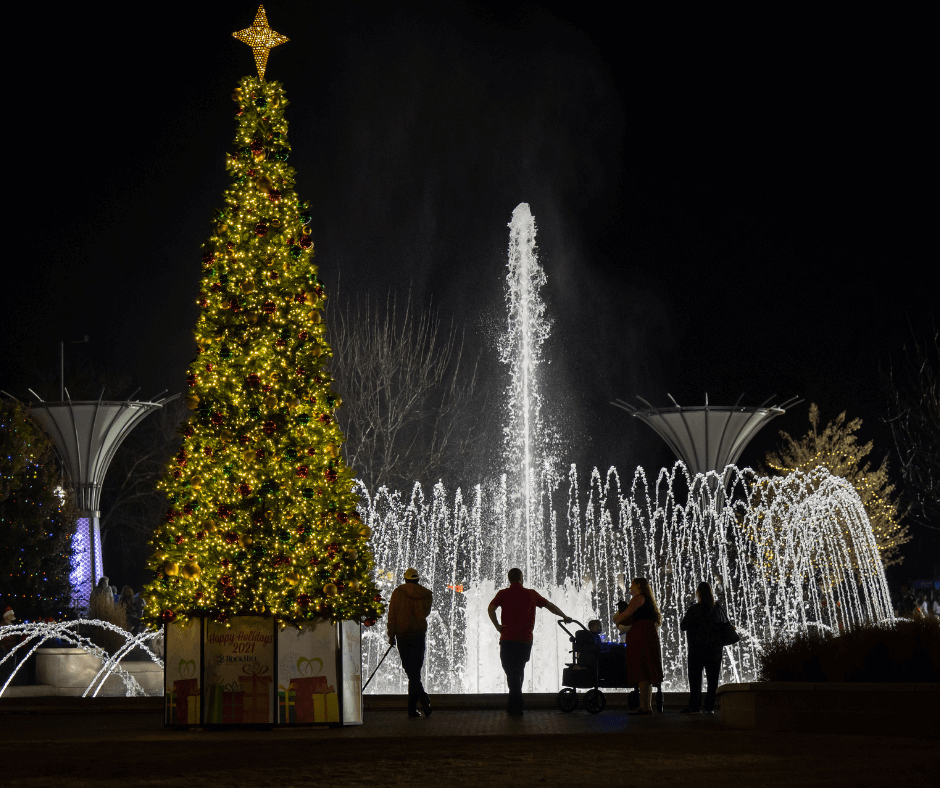 A lit Christmas tree in front of a fountain