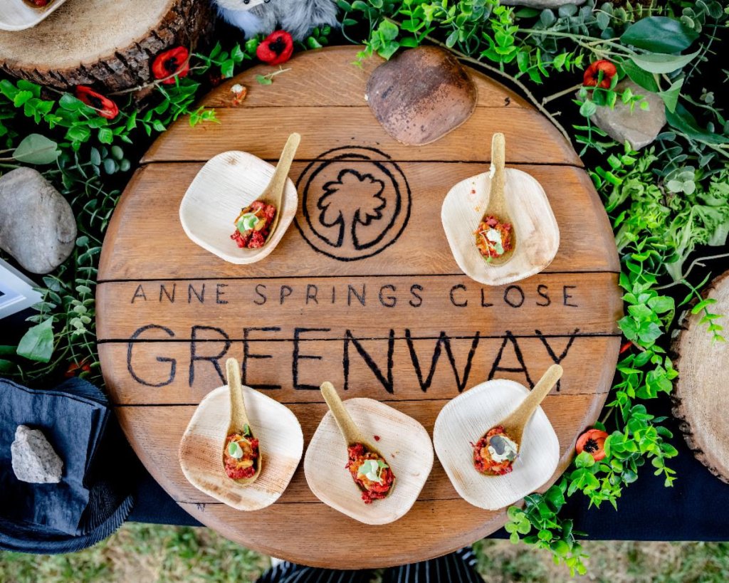 Appetizers on small wooden spoons arranged on an Anne Springs Close Greenway wooden barrel lid